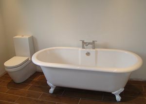 A free standing bath with mixer taps alongside a WC unit, in Nantwich, Cheshire